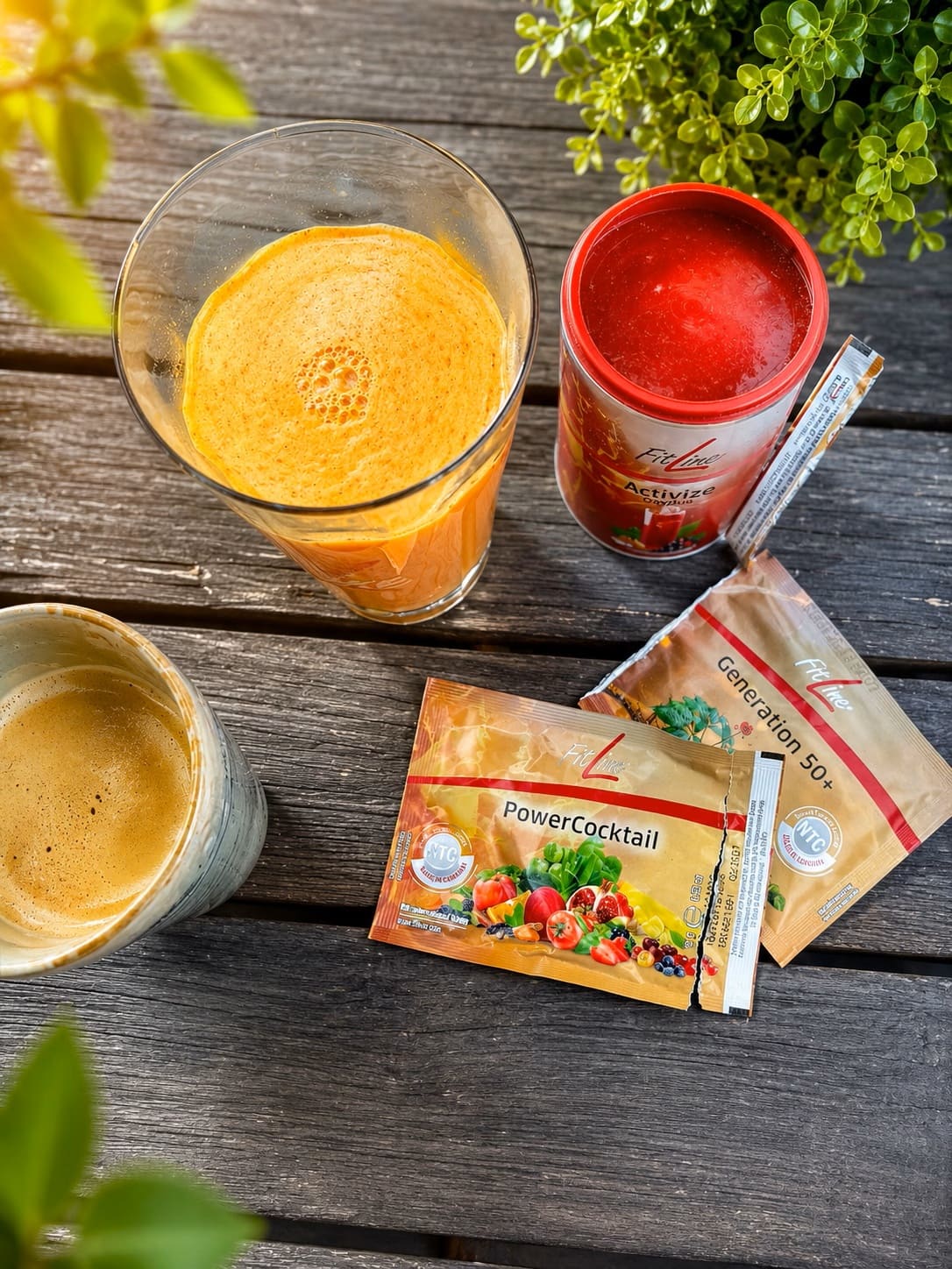 FitLine PowerCocktail und Activize mit orangem Getraenk und Kaffee auf Holztisch