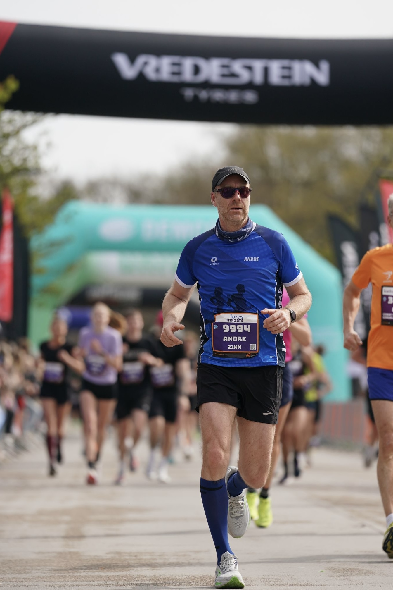 Andre in blauem Trikot und Sonnenbrille laeuft konzentriert beim Halbmarathon